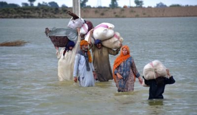 A displaced family wades through a flooded area after heavy rainfall, in Jaffarabad, a district of Pakistan's southwestern Baluchistan province, Wednesday, Aug. 24, 2022. Rains have triggered flash floods and wreaked havoc across much of Pakistan since mid-June, leaving 903 dead and about 50,000 people homeless, the country's disaster agency said Wednesday. (AP Photo/Zahid Hussain)